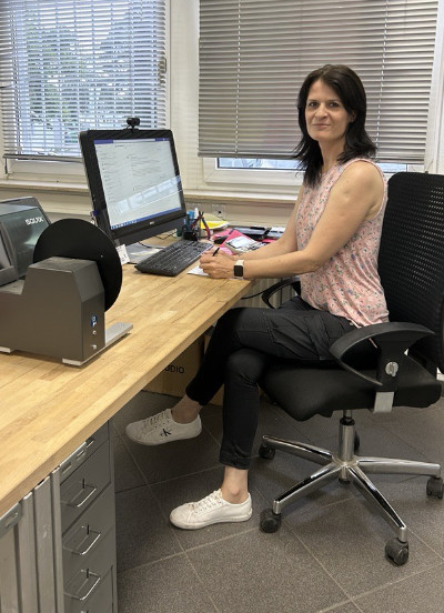 woman sitting at her desk in front of a computer looking friendly into the camera.