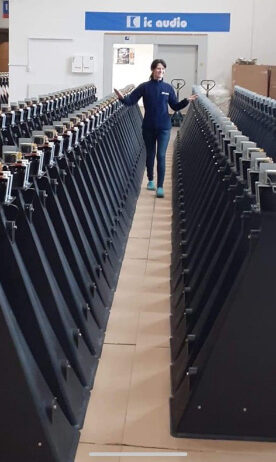 woman walking between rows of black tunnelhorn loudspeakers.